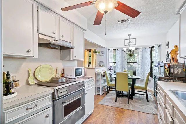 a kitchen with a stove a sink dishwasher a dining table and chairs with wooden floor