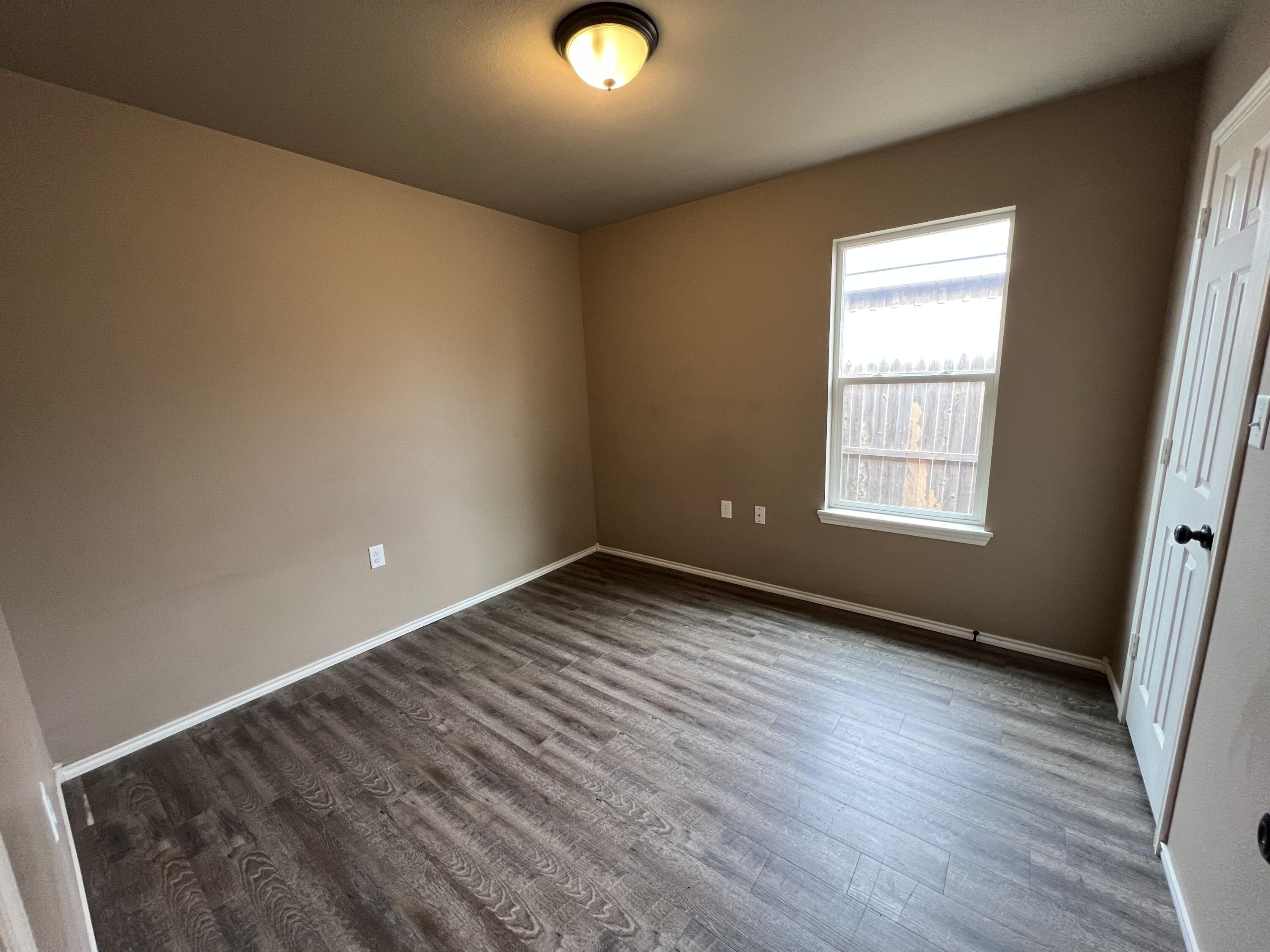 2914 East Cornell Street Lubbock, TX 79403 - Photo 8 of 18 an empty room with wooden floor and windows
