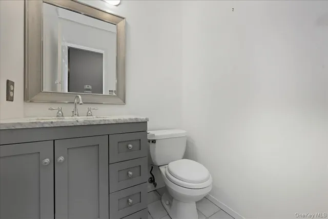 a bathroom with a granite countertop toilet sink and mirror