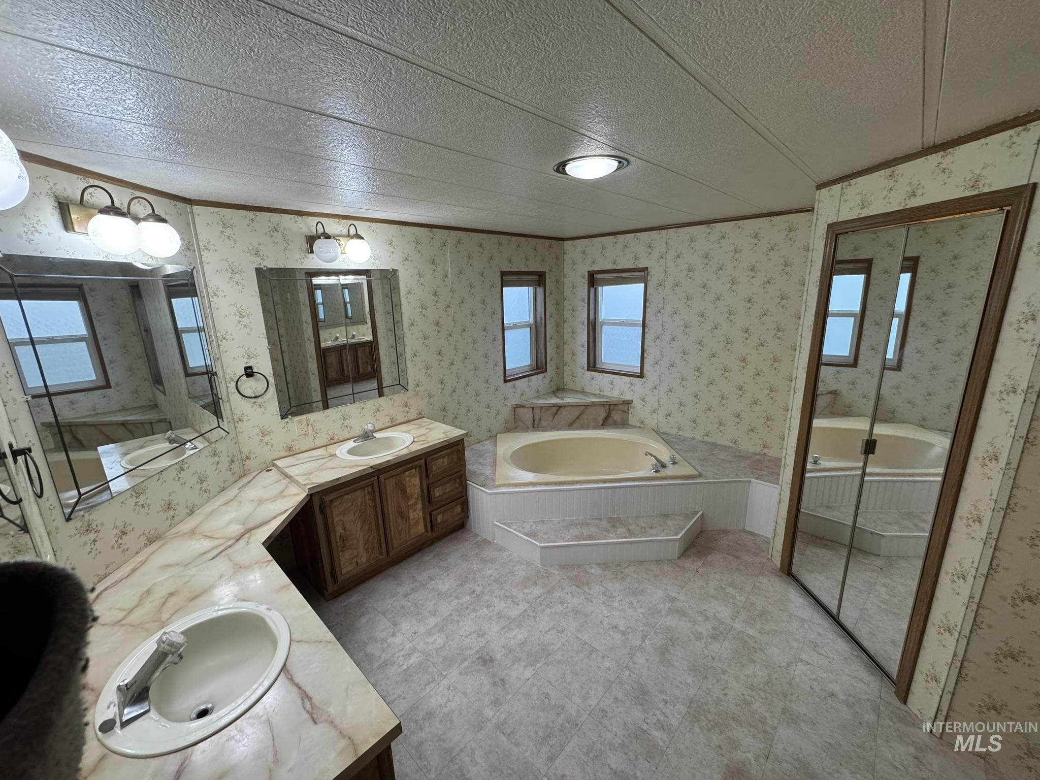 2015 6th Avenue, Unit 308 Clarkston, WA 99403 - Photo 16 of 39 Full bathroom featuring plenty of natural light, double vanity, a bath, wallpapered walls, and a textured ceiling