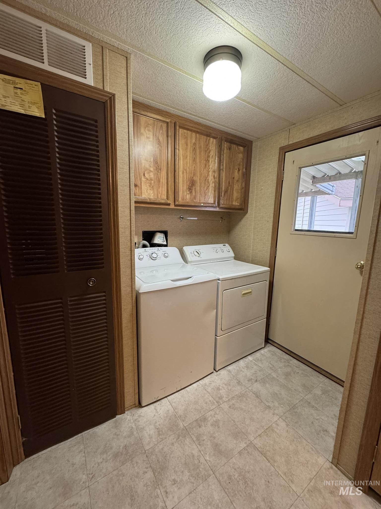 2015 6th Avenue, Unit 308 Clarkston, WA 99403 - Photo 10 of 39 Laundry area featuring cabinet space, a heating unit, washing machine and clothes dryer, light tile patterned flooring, and a textured ceiling