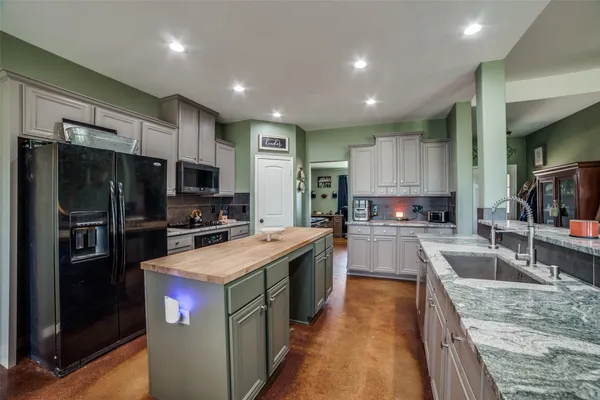 a large kitchen with stainless steel appliances granite countertop a large counter top a stove a sink and a refrigerator