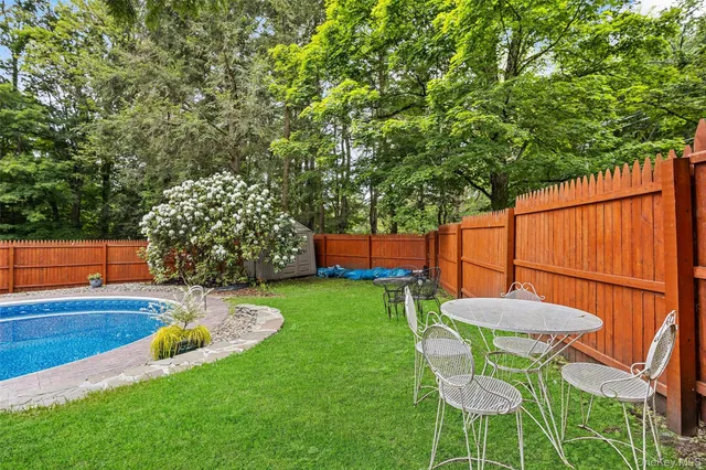 a view of a backyard with table and chairs with wooden fence and plants