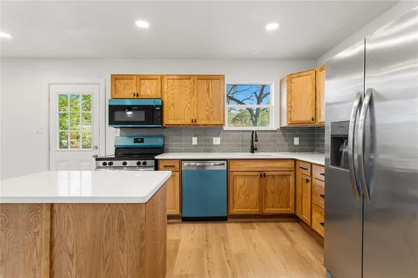 a kitchen with stainless steel appliances a refrigerator sink and microwave