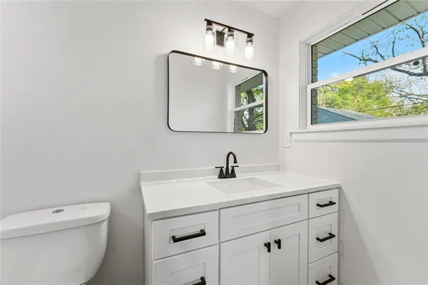 a bathroom with a toilet sink vanity and mirror