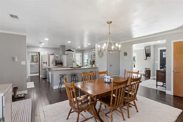 a view of a dining room and livingroom with furniture wooden floor a chandelier
