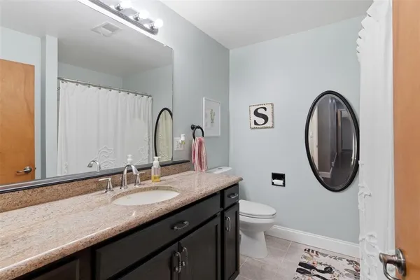 a bathroom with a granite countertop toilet a sink and a mirror