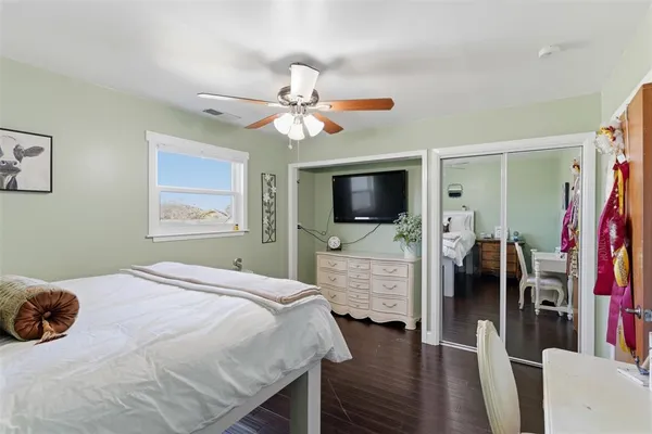 a bedroom with a bed and a flat tv screen on dresser
