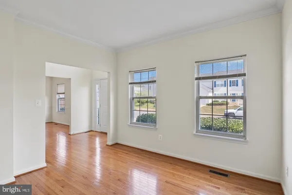 a view of an empty room with wooden floor and windows