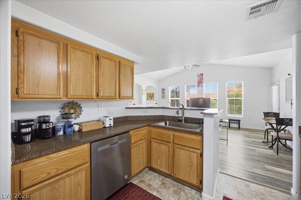 10550 West Alexander Road, Unit 2164 Las Vegas, NV 89129 - Photo 10 of 27 A functional kitchen with natural wood cabinetry and a stainless steel dishwasher flows seamlessly into an airy living area.