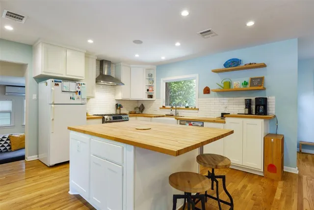 a kitchen with stainless steel appliances granite countertop a sink a stove a refrigerator and island with wooden floor