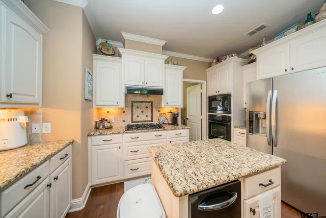 a kitchen with stainless steel appliances kitchen island granite countertop a sink stove and refrigerator