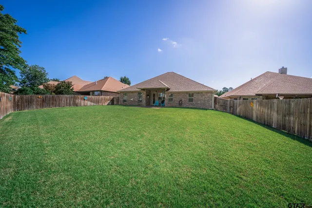 a view of a house with a yard and a large tree