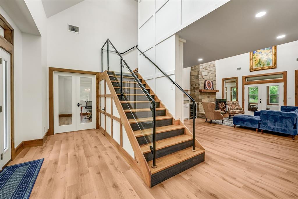 1037 Harrison Road Denison, TX 75021 - Photo 9 of 39 Grand entryway featuring a wood staircase with glass and black metal railings, leading to a spacious living area with wood-finish flooring