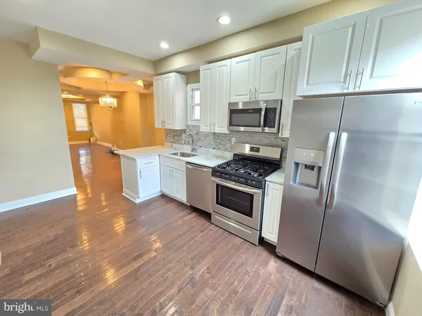 a kitchen with a sink wooden floor and stainless steel appliances