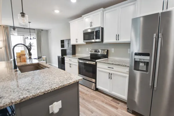 a kitchen with stainless steel appliances granite countertop a refrigerator a stove top oven a sink and dishwasher