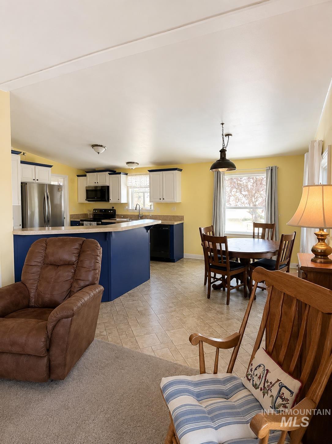 2750 Alden Road, Unit 12 12 Fruitland, ID 83619 - Photo 8 of 38 Open-concept living space featuring a kitchen with white cabinetry and dark blue base cabinets, stainless steel refrigerator, black range, and light-toned countertops