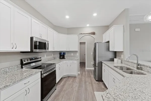 a kitchen with granite countertop a sink a counter top space stainless steel appliances and cabinets