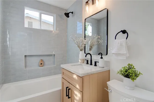 a bathroom with a sink and mirror with bathtub