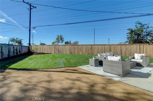 a view of a patio with couches chairs and wooden fence