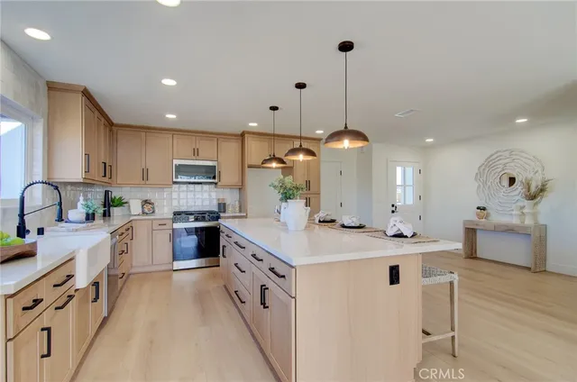 a large kitchen with kitchen island a stove a sink a center island and a wooden floor