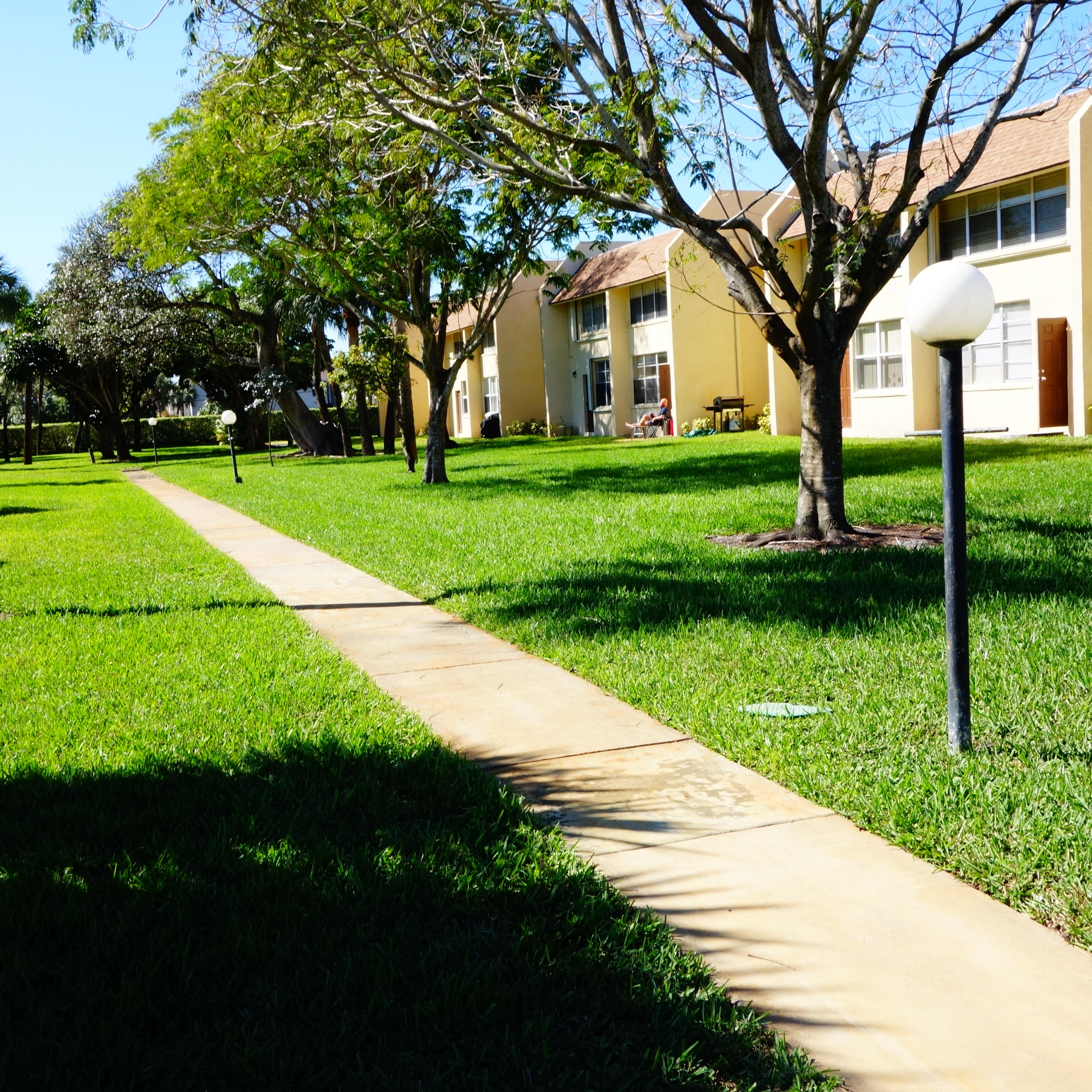 2805 Southwest 22nd Avenue, Unit 2060 Delray Beach, FL 33445 - Photo 9 of 11 a view of a house with a big yard and large trees