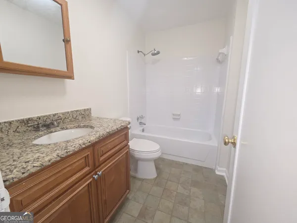 a bathroom with a granite countertop sink a toilet and shower