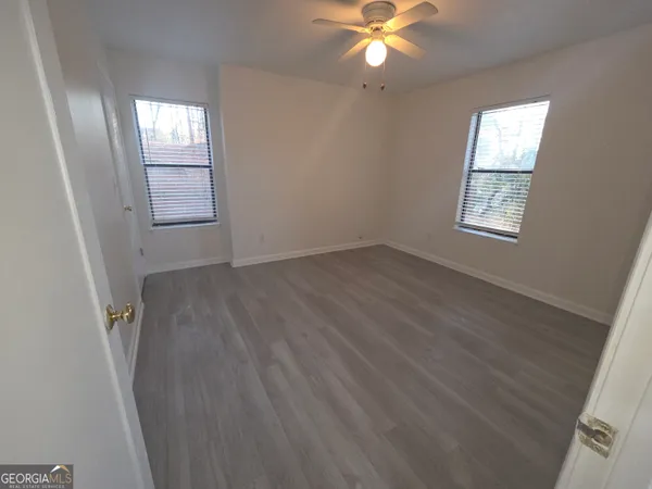 a view of an empty room with wooden floor and a window