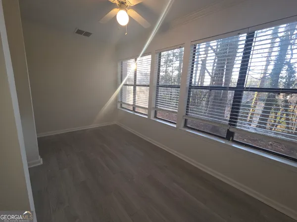 an empty room with wooden floor and windows