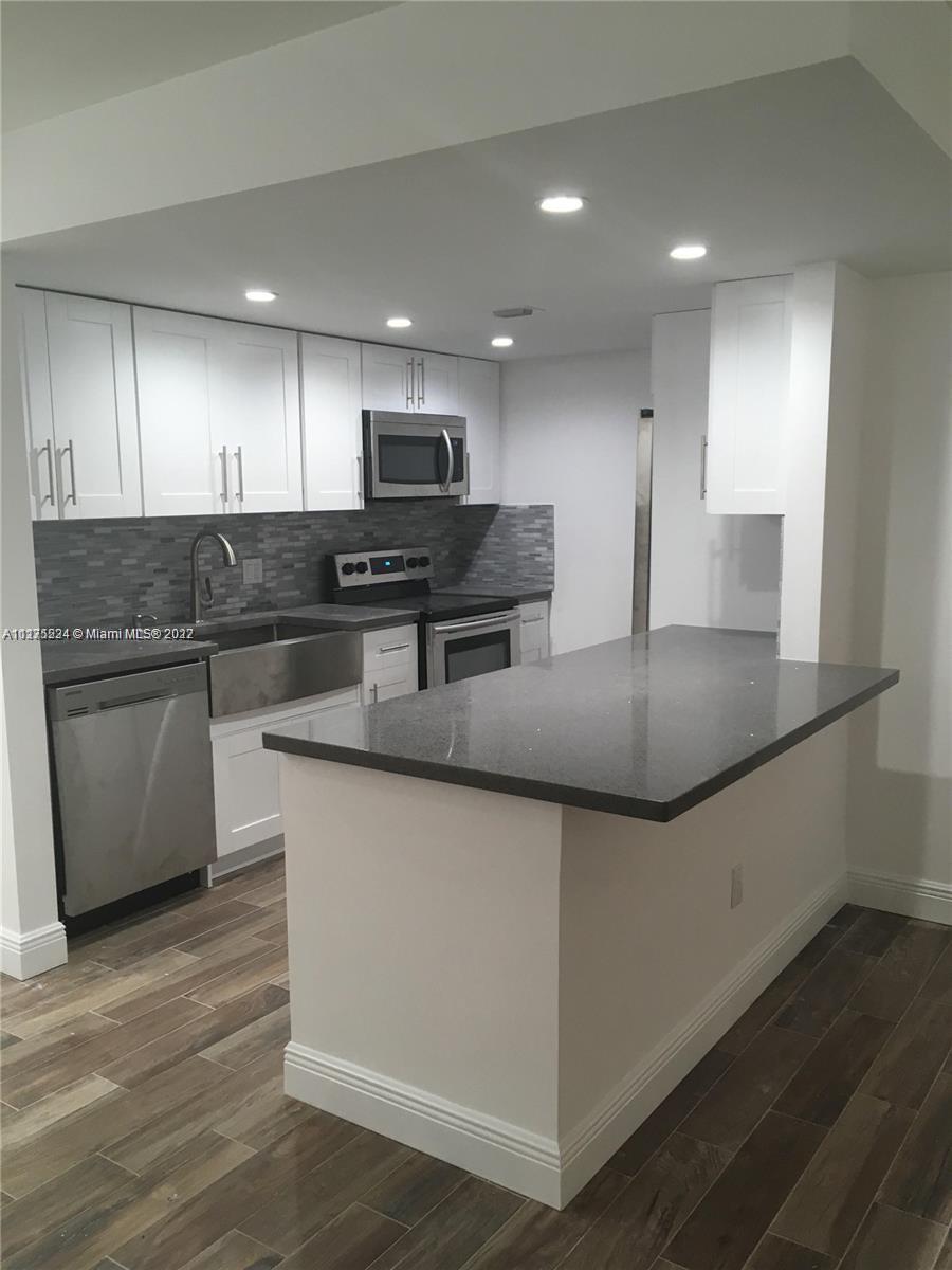 a kitchen with stainless steel appliances granite countertop a sink a stove top oven a counter space and cabinets