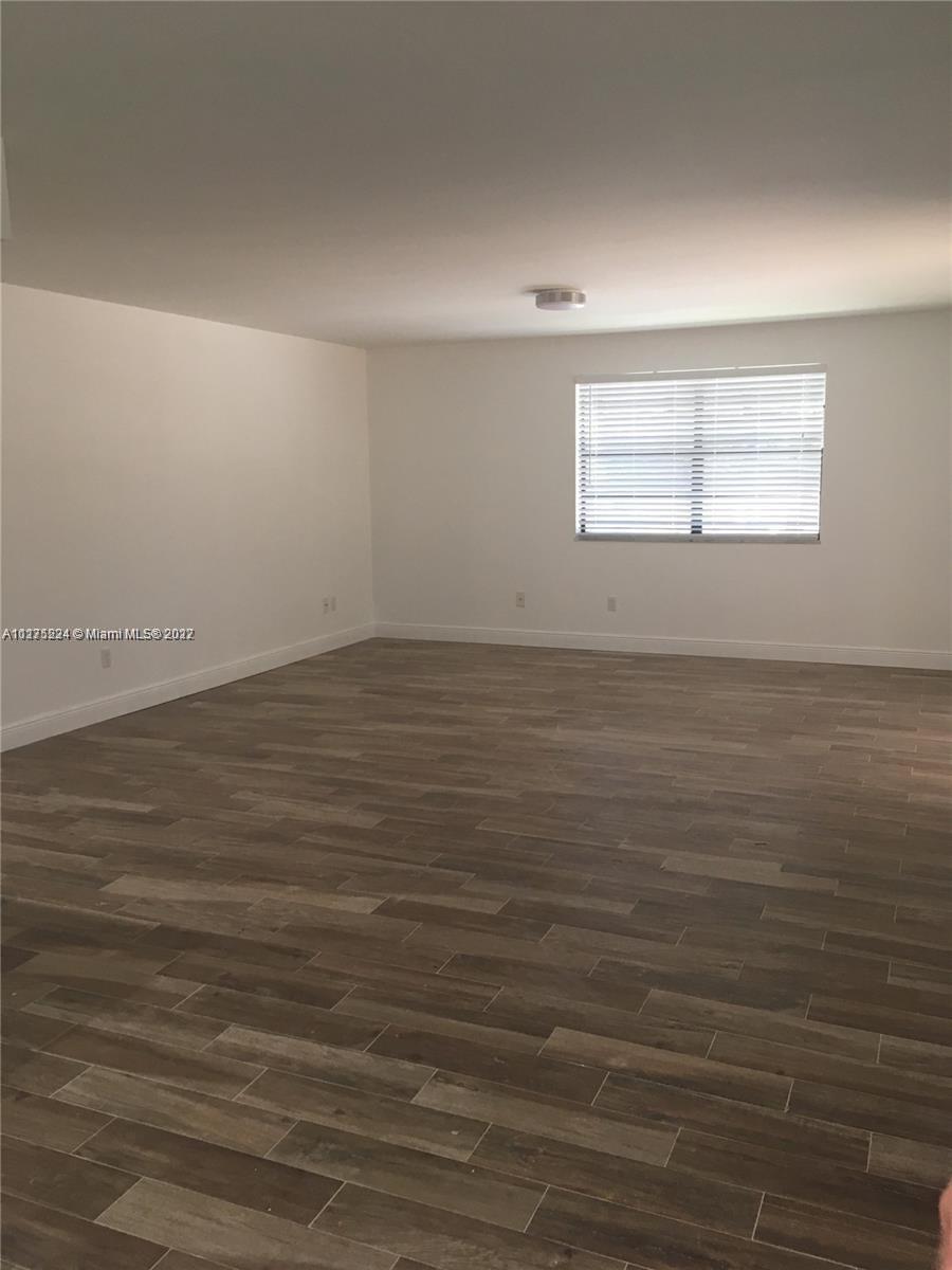 7915 Southwest 86th Street, Unit 723 Miami, FL 33143 - Photo 4 of 14 an empty room with wooden floor and windows