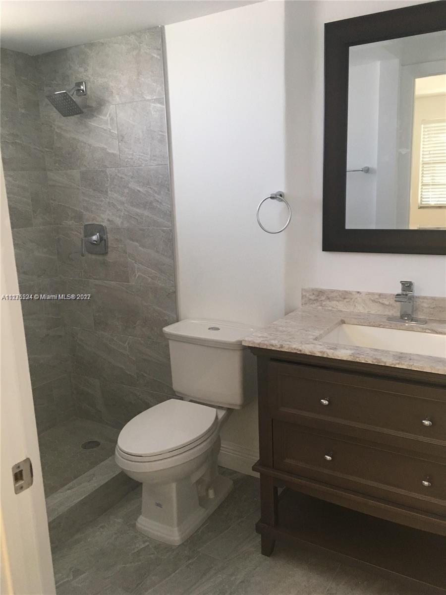 7915 Southwest 86th Street, Unit 723 Miami, FL 33143 - Photo 7 of 14 a bathroom with a granite countertop toilet sink and a mirror
