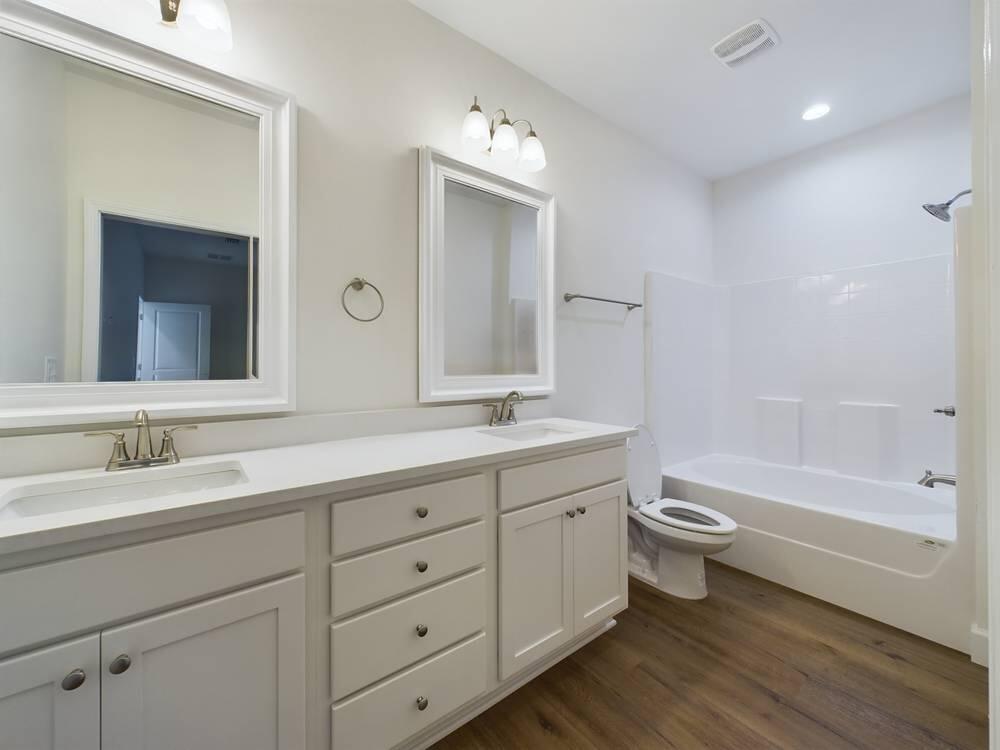 21 D 5th Avenue Shalimar, FL 32579 - Photo 12 of 18 a bathroom with a toilet a double vanity sink a mirror and a bathtub
