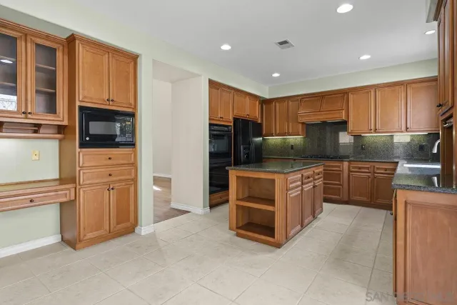 a kitchen with kitchen island a counter top space a sink stainless steel appliances and cabinets