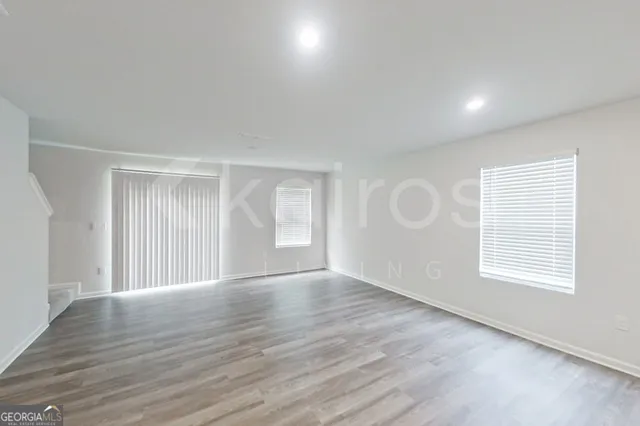 a view of an empty room with wooden floor and windows
