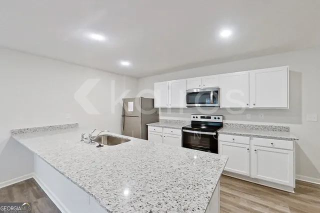 a kitchen with stainless steel appliances granite countertop white cabinets and a stove