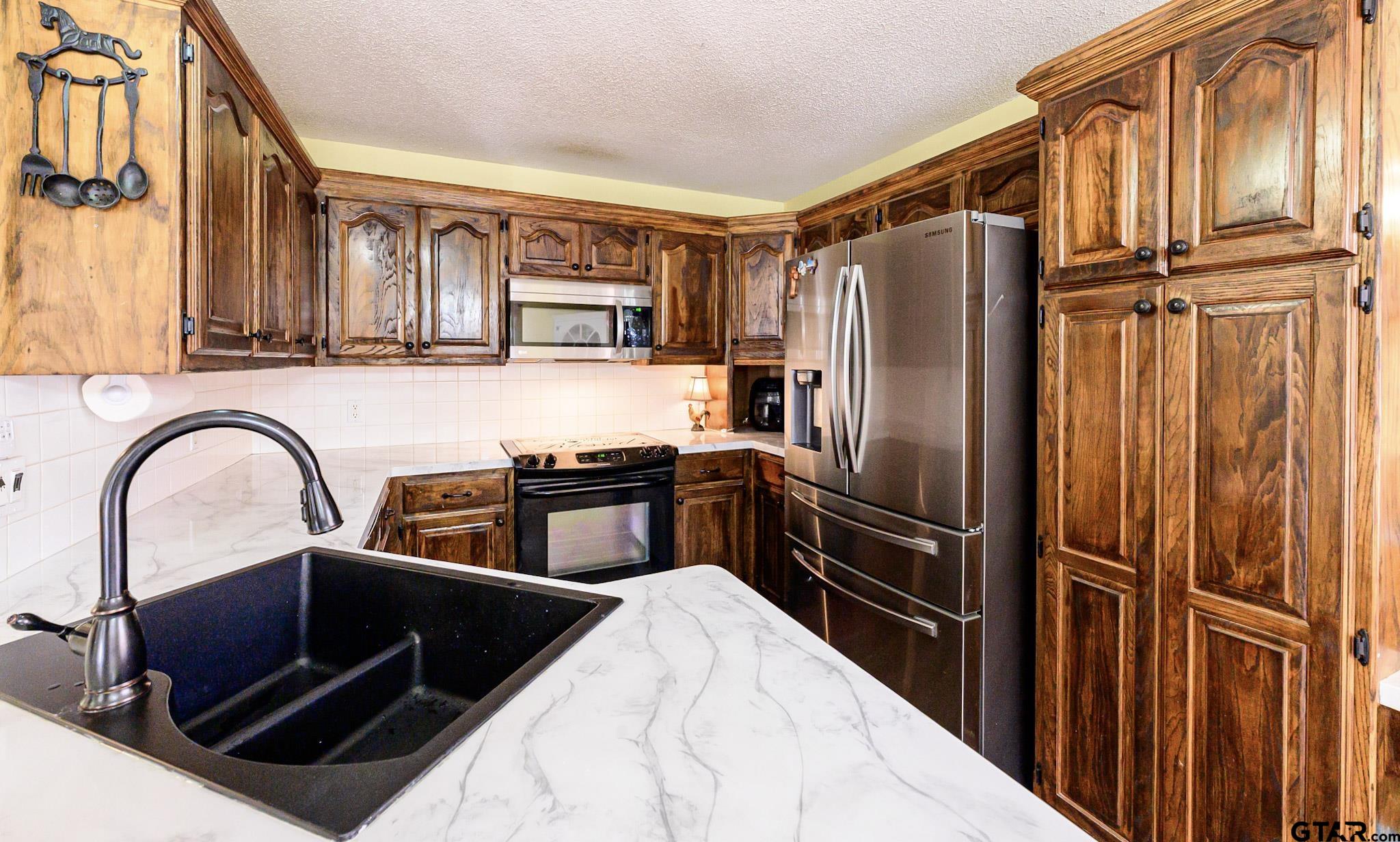 703 Kickapoo Road Chandler, TX 75758 - Photo 7 of 33 a kitchen with stainless steel appliances a refrigerator and a stove top oven