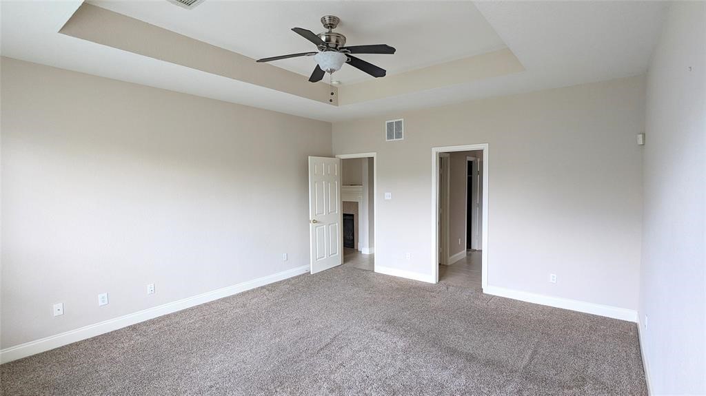20909 Springport Court Katy, TX 77450 - Photo 15 of 39 Spacious bedroom with plush carpeting, neutral walls, and a stylish tray ceiling featuring a modern ceiling fan.