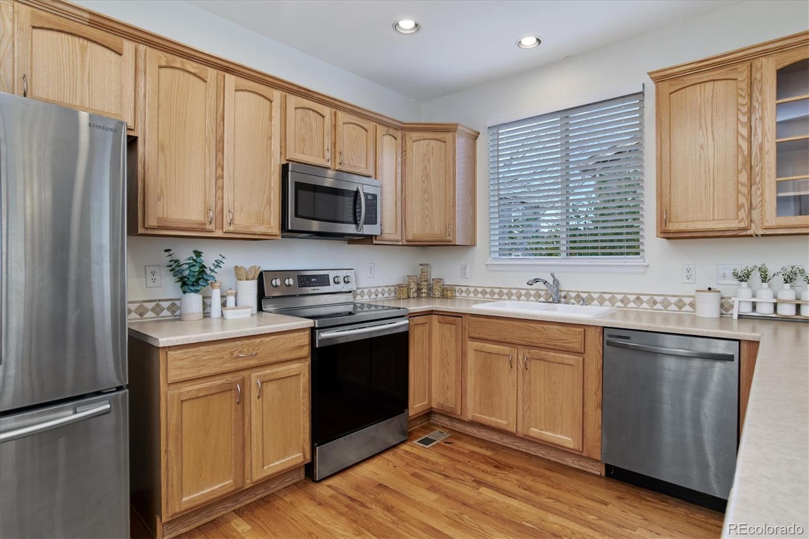 10781 Towerbridge Circle Highlands Ranch, CO 80130 - Photo 16 of 30 a kitchen with stainless steel appliances granite countertop a stove top oven a sink dishwasher and a refrigerator with wooden cabinets