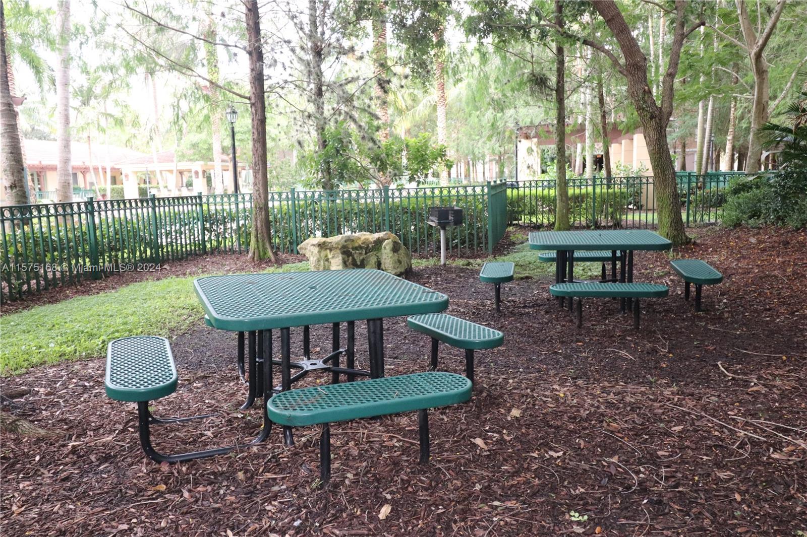 6894 West Sample Road, Unit 6894 Coral Springs, FL 33067 - Photo 1 of 18 a view of a backyard with table and chairs potted plants and a tree