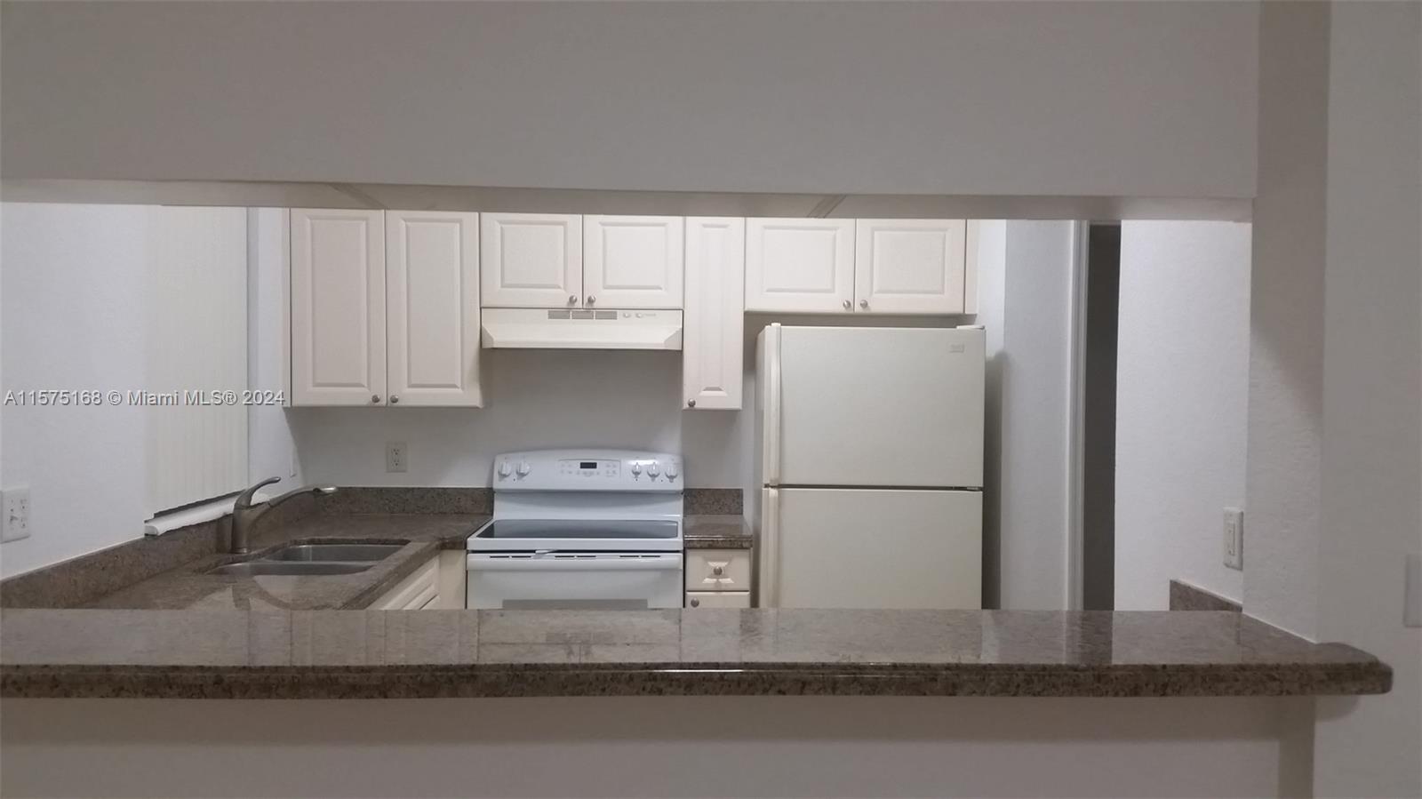 6894 West Sample Road, Unit 6894 Coral Springs, FL 33067 - Photo 8 of 18 a kitchen with a refrigerator and white cabinets