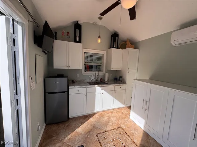 a kitchen with kitchen island granite countertop a refrigerator a sink and white cabinets