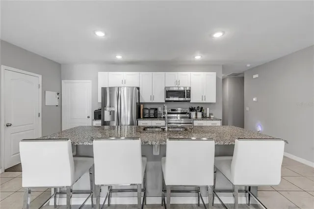 a kitchen with stainless steel appliances kitchen island granite countertop a kitchen island a white cabinets a sink and a stove