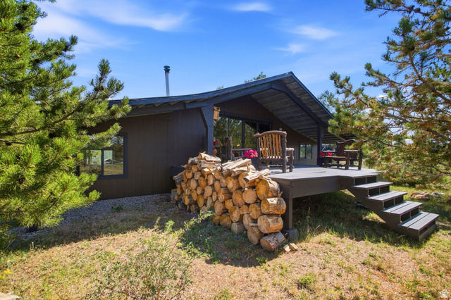 1663 Lancer Lane Evanston, UT 82930 - Photo 27 of 101 Exterior featuring a covered deck, wood siding, a metal chimney, and surrounding mature trees