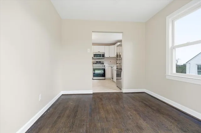 a view of empty room with wooden floor and window