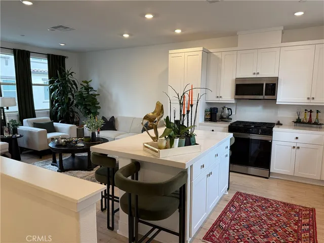 a kitchen with stainless steel appliances kitchen island granite countertop a stove a sink a microwave a dining table and chairs