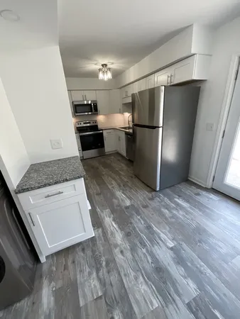 a kitchen with granite countertop a refrigerator and a stove top oven