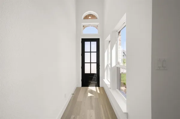 an empty room with wooden floor mirror and windows