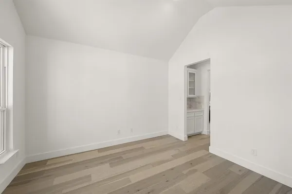 a large kitchen with a stove a sink a refrigerator and white cabinets with wooden floor