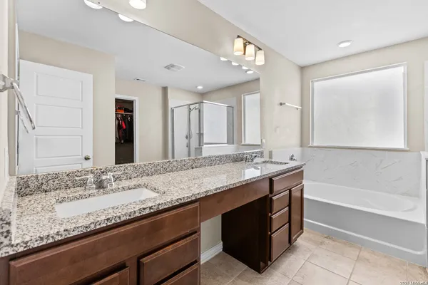a bathroom with a granite countertop bathtub sink double and mirror